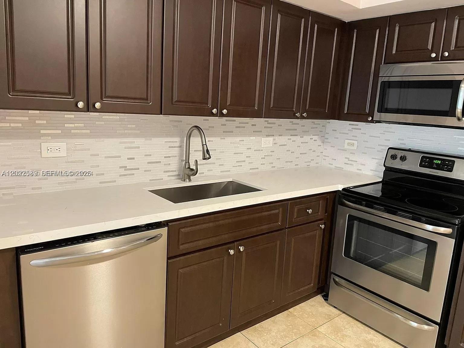 A kitchen features dark wood cabinets, stainless steel appliances, and a white countertop — 3690 N 56th Ave # 916, Hollywood FL 33021, HOLLYWOOD, FL
