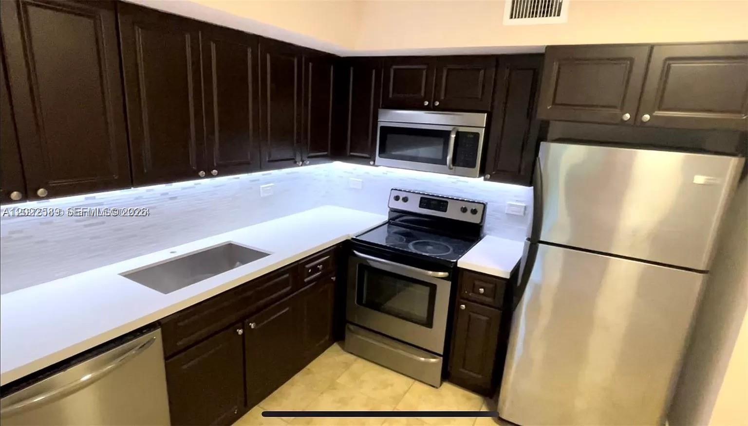 A kitchen features dark wood cabinets, stainless steel appliances, and white countertops — 3690 N 56th Ave # 916, Hollywood FL 33021, HOLLYWOOD, FL