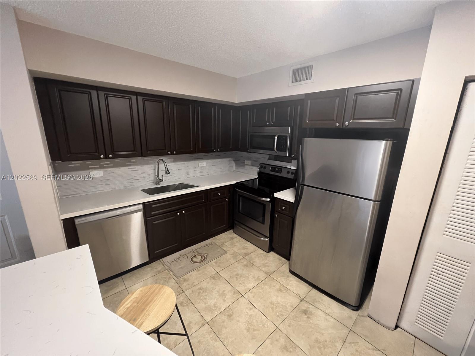 A kitchen features dark wood cabinets, stainless steel appliances, and light-colored tile flooring — 3690 N 56th Ave # 916, Hollywood FL 33021, HOLLYWOOD, FL