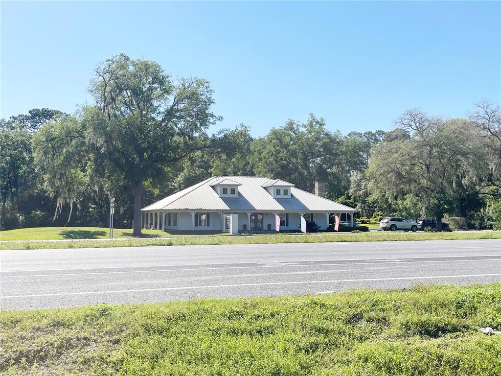 A single-story building with a metal roof sits behind a multi-lane road and trees — 21848 S COUNTY ROAD 325, HAWTHORNE, FL
