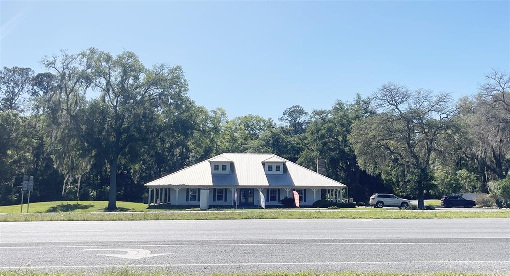 A single-story white building with a metal roof sits behind a multi-lane road — 21848 S COUNTY ROAD 325, HAWTHORNE, FL