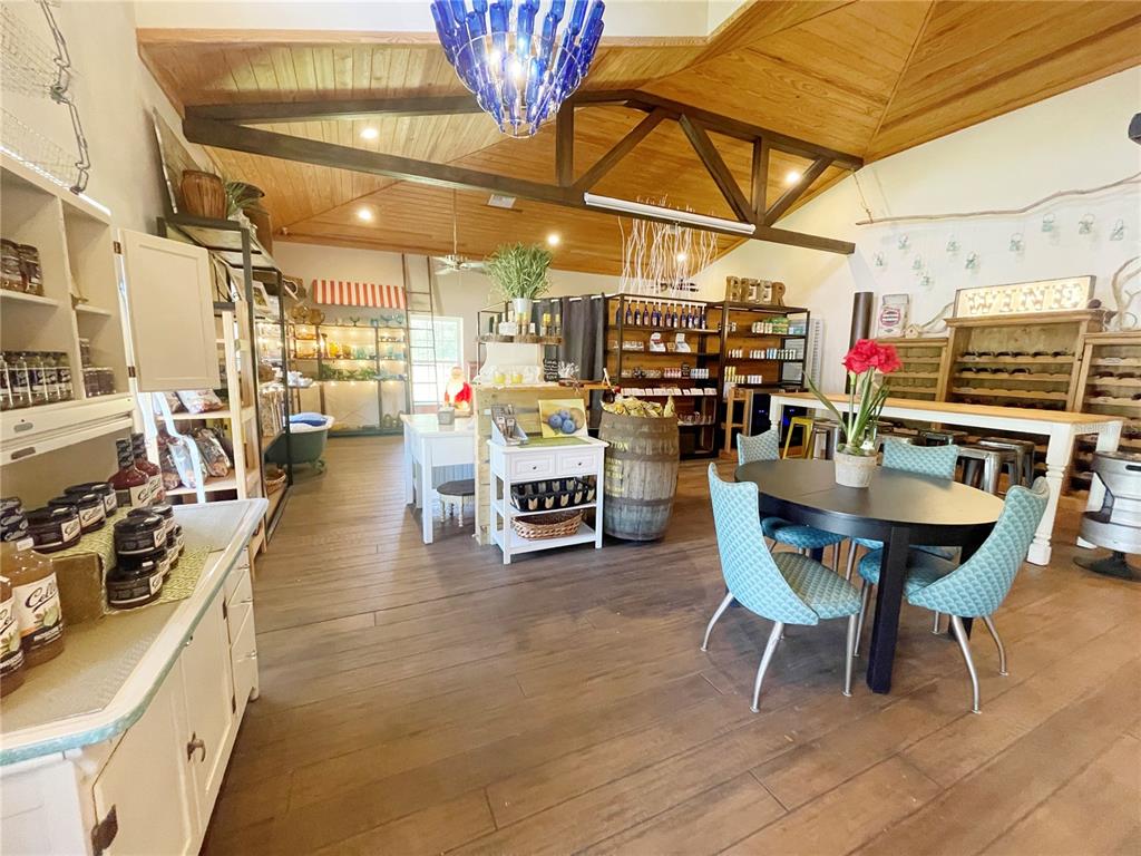 A rustic retail space features wood-paneled vaulted ceilings, a blue bottle chandelier, and dining furniture — 21848 S COUNTY ROAD 325, HAWTHORNE, FL