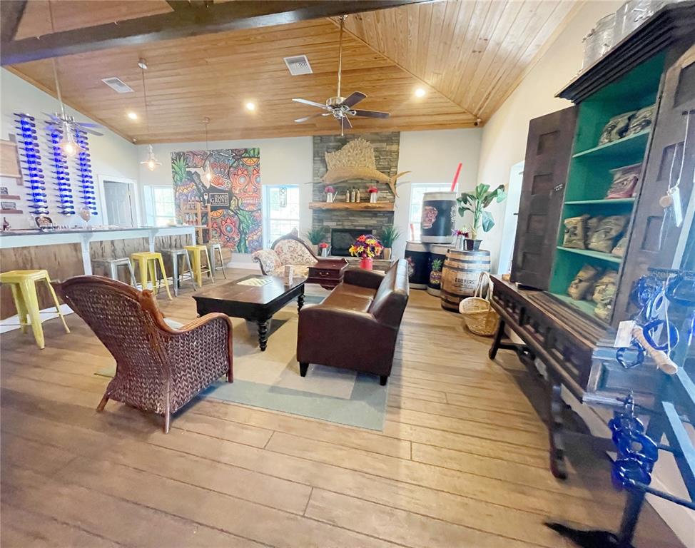 This rustic lounge features a wood-paneled ceiling, stone fireplace, bar area, and assorted seating — 21848 S COUNTY ROAD 325, HAWTHORNE, FL