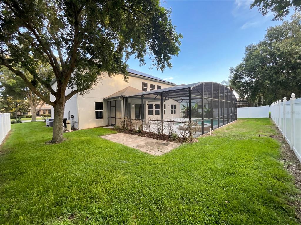 A two-story house features a screened-in pool enclosure and a paved patio in the backyard — 15130 OVATION DRIVE, WINTER GARDEN, FL
