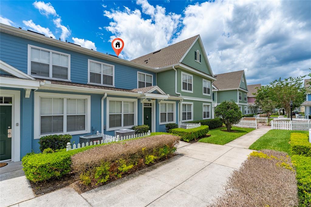 The exterior of a blue and green multi-story townhouse with a sidewalk and landscaping — 4017 VENETIAN BAY DRIVE UNIT 103, KISSIMMEE, FL