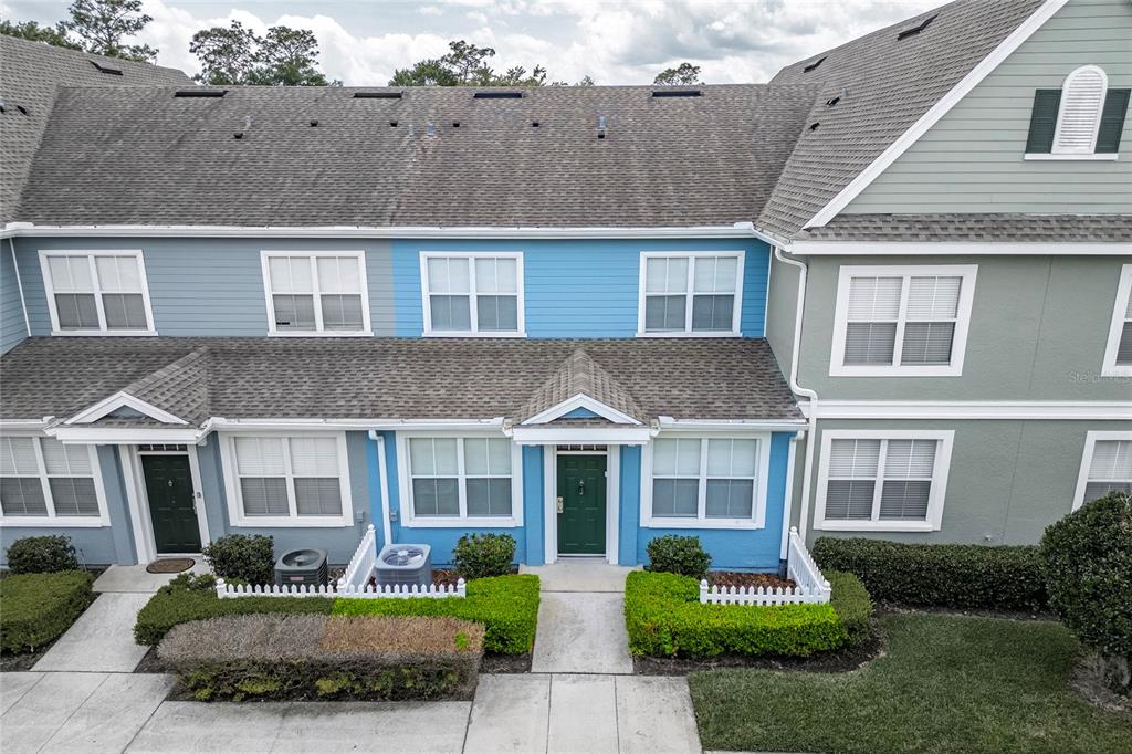 An exterior view of a two-story townhouse with blue siding, green doors, and white trim — 4017 VENETIAN BAY DRIVE UNIT 103, KISSIMMEE, FL