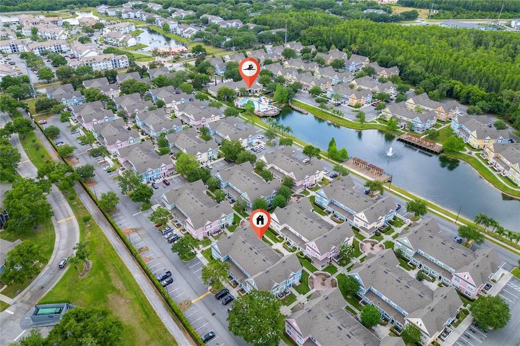 This aerial view shows a residential community with townhomes, a swimming pool, and a lake — 4017 VENETIAN BAY DRIVE UNIT 103, KISSIMMEE, FL
