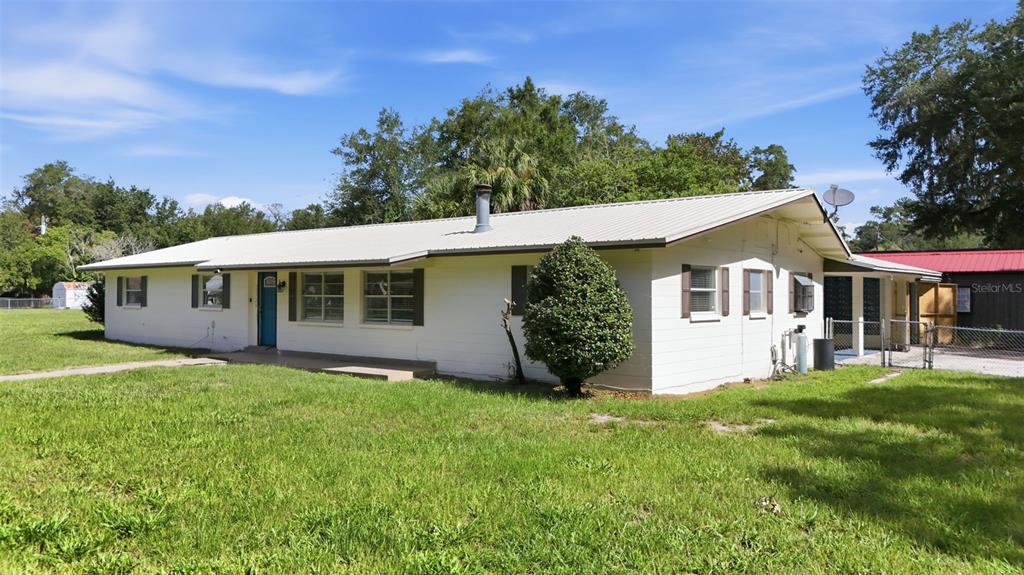 A white single-story house with a metal roof sits on a grassy lot — 22526 SE 62ND AVENUE, HAWTHORNE, FL