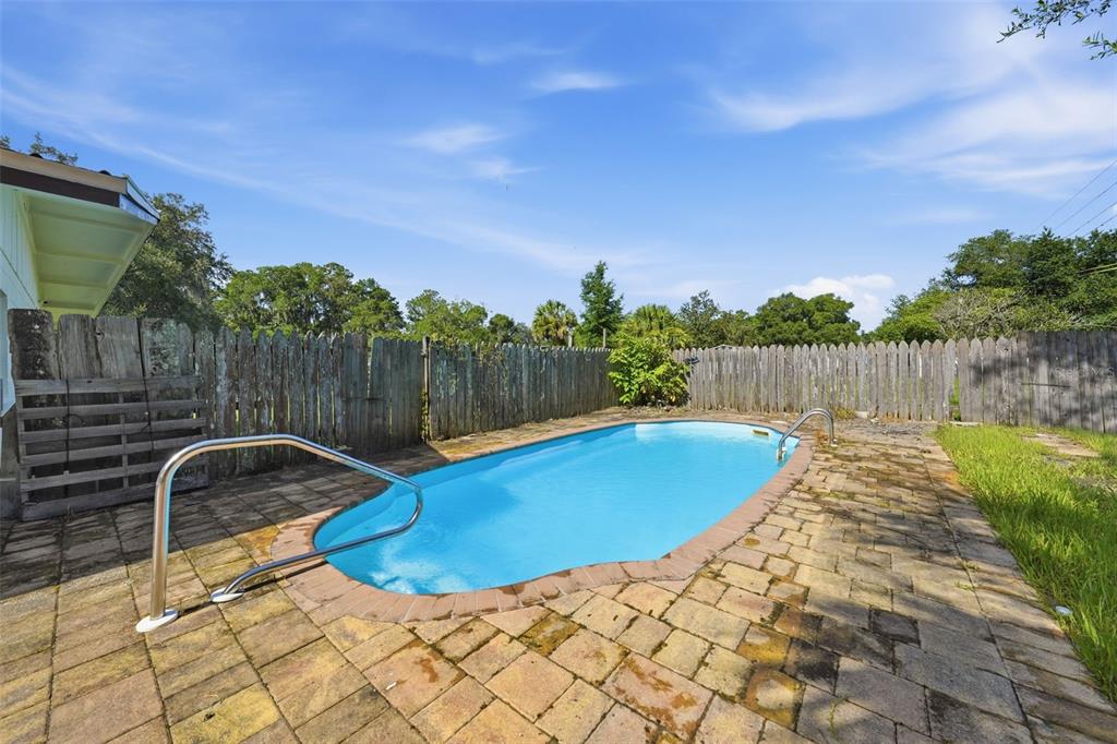 An outdoor swimming pool with a brick paver deck and a wooden fence — 22526 SE 62ND AVENUE, HAWTHORNE, FL