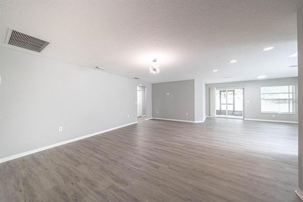 An open-concept living area features light gray walls, wood-look flooring, and recessed lighting — 2025 PEACEFUL PALM STREET, RUSKIN, FL