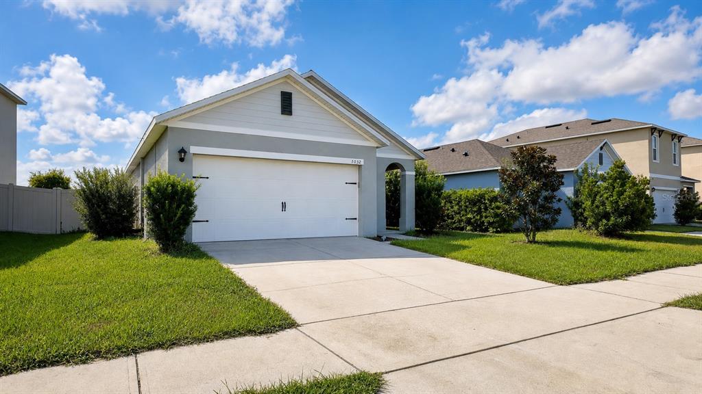 A single-story suburban house features a white garage door, light gray siding, and a driveway — 1032 ANDEAN LANE, DAVENPORT, FL