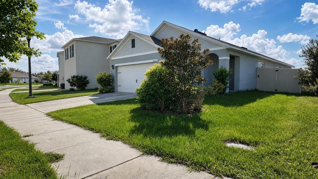 A single-story suburban house with a two-car garage, light siding, and a manicured lawn — 1032 ANDEAN LANE, DAVENPORT, FL