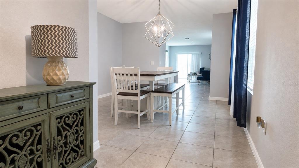 A dining area with a wooden table, chairs, bench, and a geometric pendant light fixture — 1032 ANDEAN LANE, DAVENPORT, FL