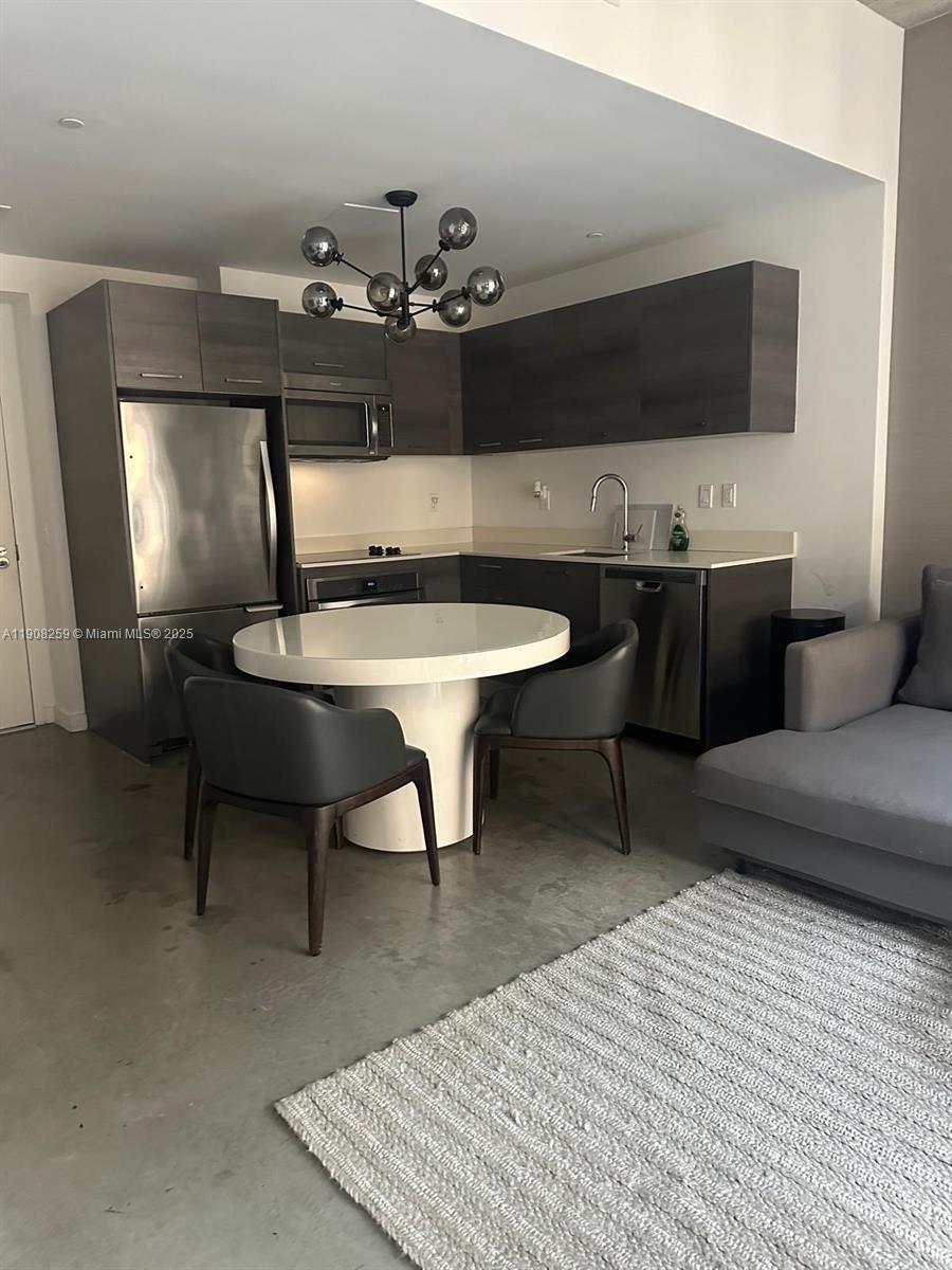 A modern kitchen features dark wood cabinets, stainless steel appliances, and a round dining table — 151 SE 1st St # 903, Miami FL 33131, MIAMI, FL