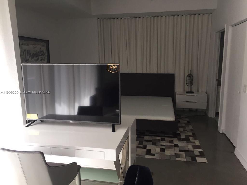 A bedroom features a television on a desk, a bed, and a patterned area rug — 151 SE 1st St # 903, Miami FL 33131, MIAMI, FL