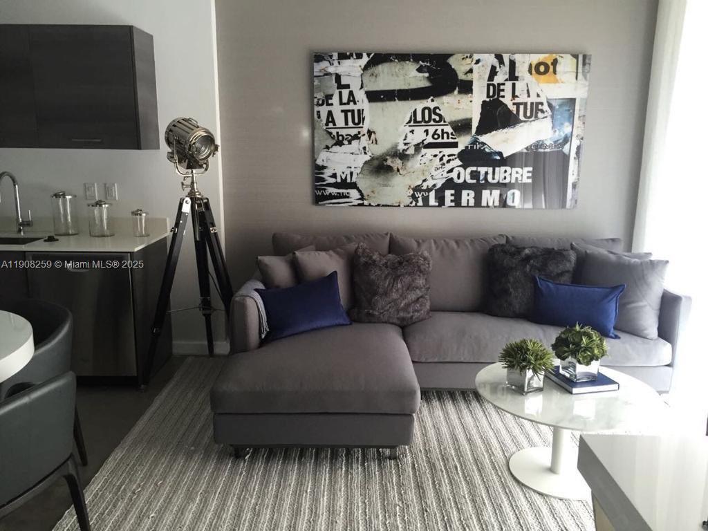 A living room features a grey sectional sofa, a tripod floor lamp, and wall art — 151 SE 1st St # 903, Miami FL 33131, MIAMI, FL