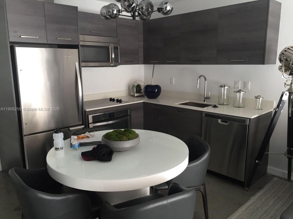 A modern kitchen features dark wood cabinetry, stainless steel appliances, and a white dining table — 151 SE 1st St # 903, Miami FL 33131, MIAMI, FL