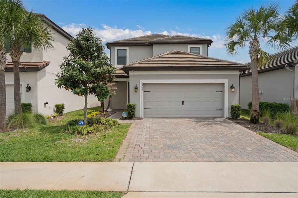 A two-story suburban house features a paved driveway, a two-car garage, and palm trees — 1369 BLUE STEM LANE, WINTER PARK, FL