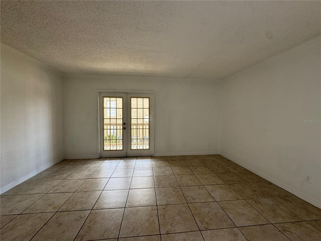 An empty room features white walls, a textured ceiling, and light-colored square floor tiles — 355 WYMORE ROAD UNIT 202, ALTAMONTE SPRINGS, FL