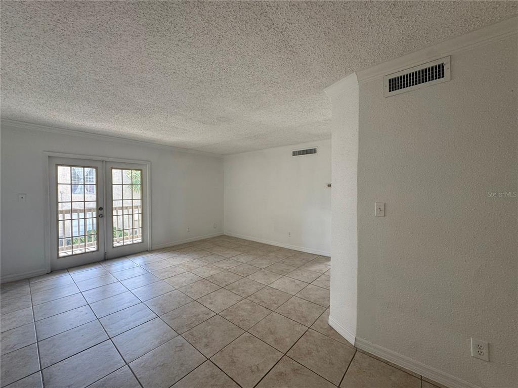 An empty room with beige tile flooring, white walls, and glass double doors — 355 WYMORE ROAD UNIT 202, ALTAMONTE SPRINGS, FL