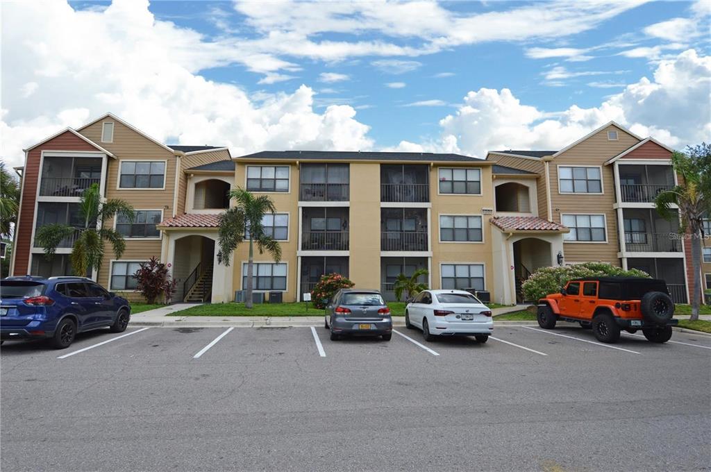 A three-story apartment building with tan siding and a parking lot in front — 11901 4TH STREET N UNIT 9105, ST PETERSBURG, FL