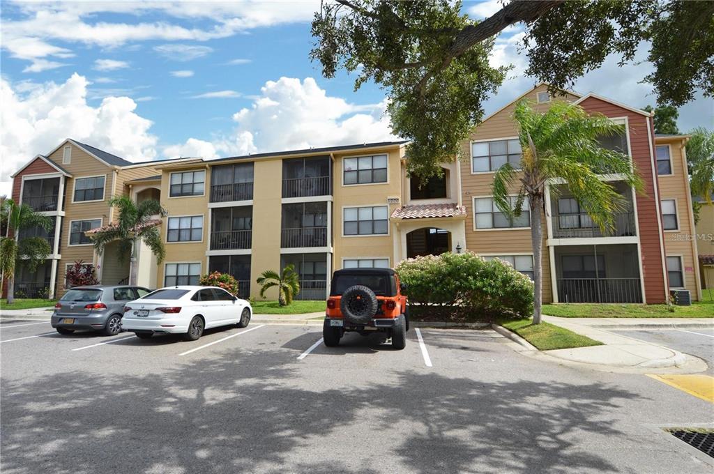 A three-story apartment building with tan siding and a parking lot in the foreground — 11901 4TH STREET N UNIT 9105, ST PETERSBURG, FL