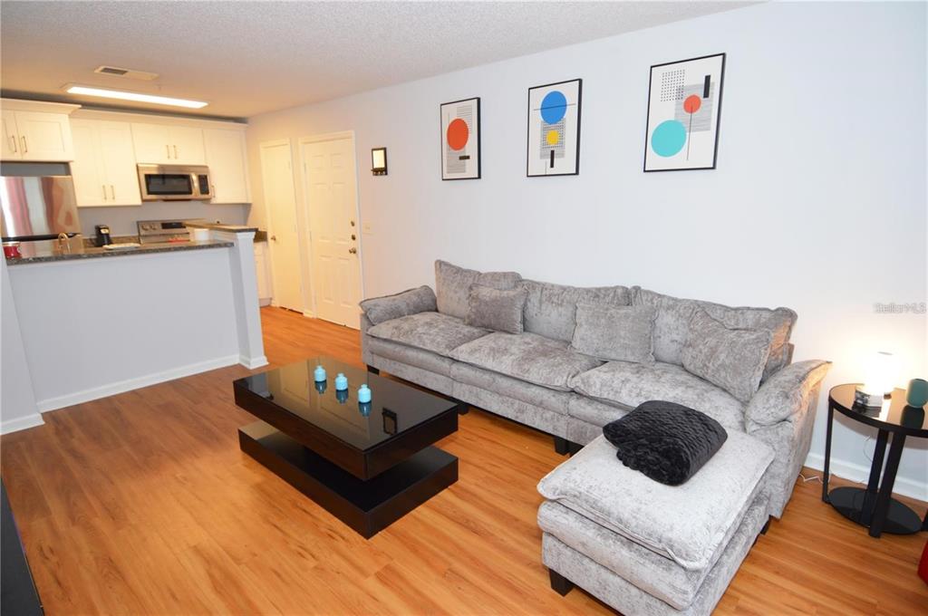 A living room with wood flooring, a gray sectional sofa, and a black coffee table — 11901 4TH STREET N UNIT 9105, ST PETERSBURG, FL