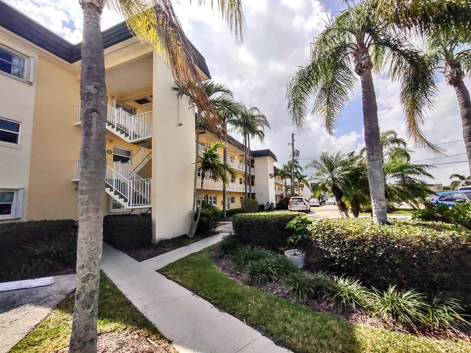 A multi-story apartment building with exterior staircases, palm trees, and a concrete walkway — 1351 Bayshore Drive # 108, Fort Pierce FL 34949, FORT PIERCE, FL