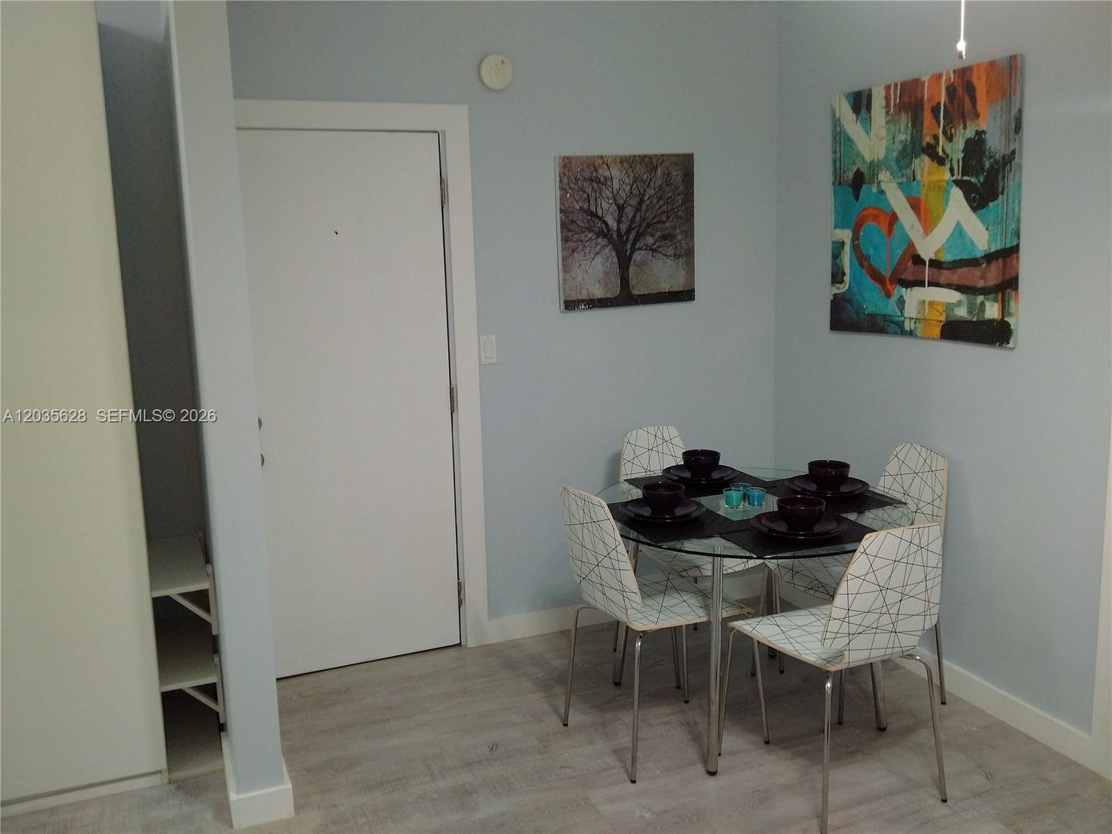 A dining area features a glass table with four patterned chairs and two wall paintings — 1525 Meridian Ave # 104, Miami Beach FL 33139, MIAMI BEACH, FL