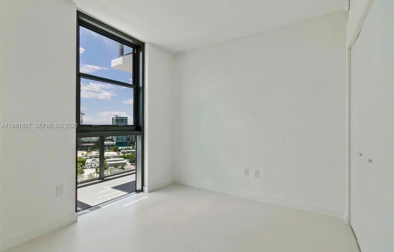 A minimalist bedroom features white walls, white tile flooring, and a large floor-to-ceiling window — 501 NE 31st St # 1808, Miami FL 33137, MIAMI, FL