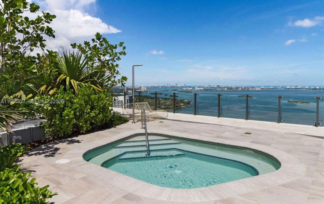 A rooftop hot tub sits on a stone patio overlooking a bay and city skyline — 501 NE 31st St # 1808, Miami FL 33137, MIAMI, FL
