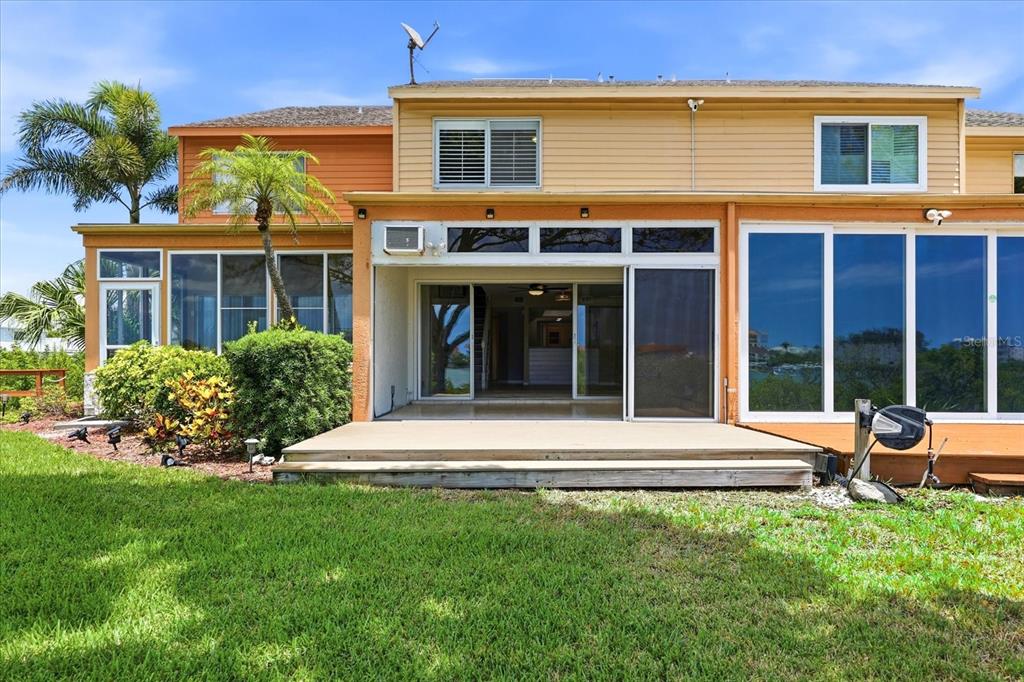 The exterior of a two-story house features a wooden deck, sliding glass doors, and landscaping — 14628 LORIDAWN DRIVE UNIT 13, SEMINOLE, FL