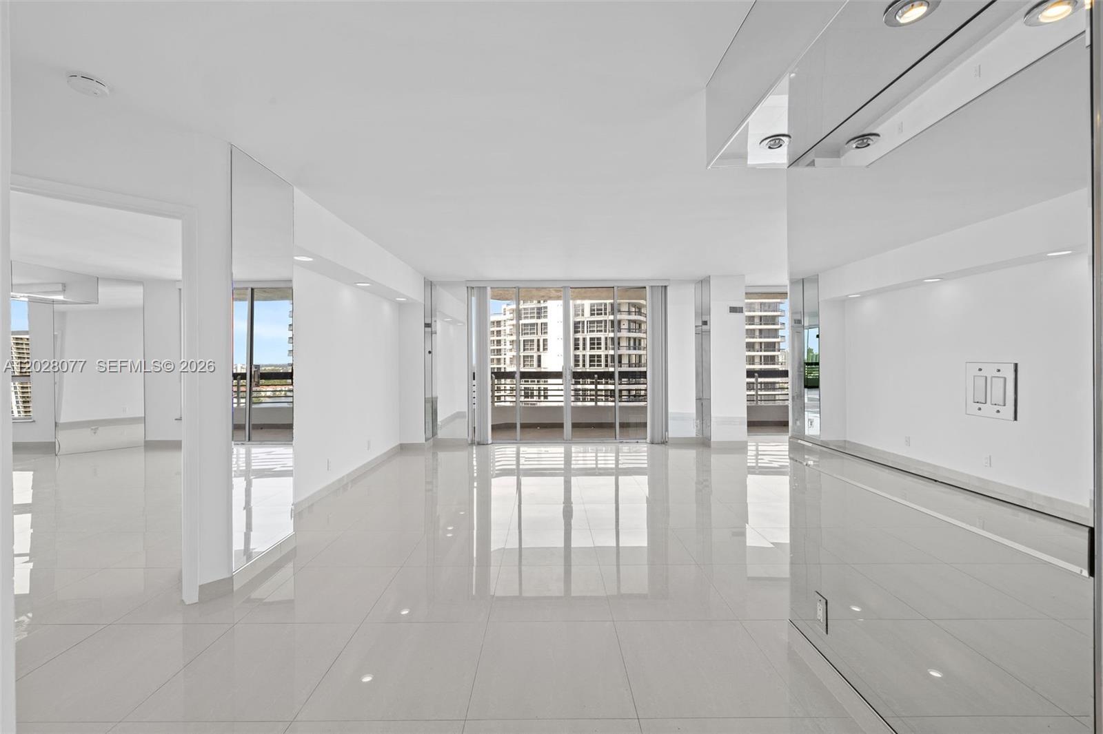 A bright, empty living room features white walls, glossy tile floors, and floor-to-ceiling windows — 19195 NE 36th Ct # 2705, Aventura FL 33180, AVENTURA, FL
