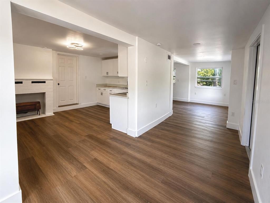 An interior view shows a living area with a fireplace, kitchen, and wood-look flooring — 7211 JAMES STREET, PORT RICHEY, FL