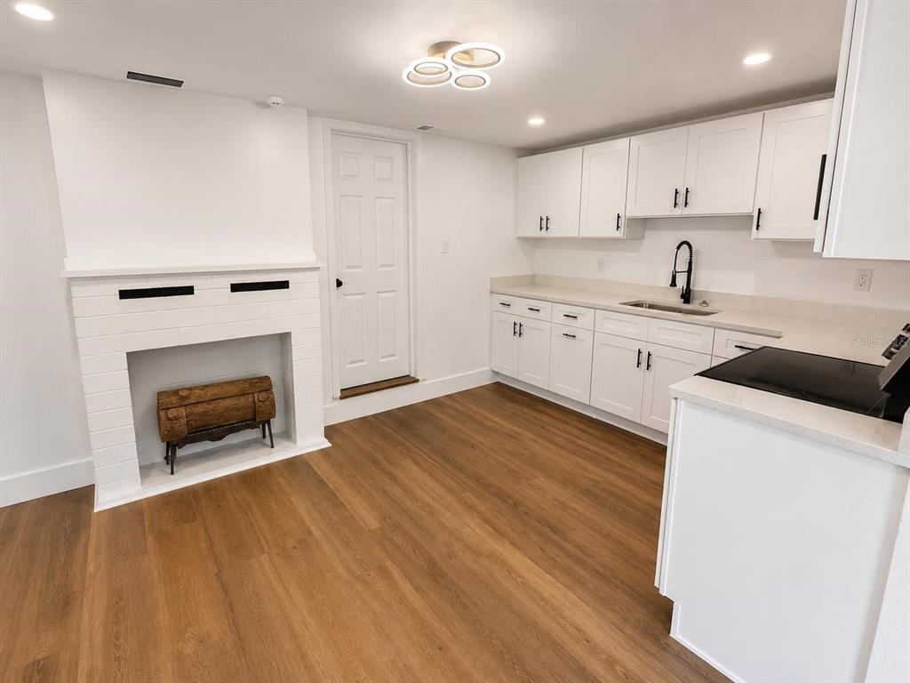A kitchen features white cabinets, a sink, a fireplace, and wood-look flooring — 7211 JAMES STREET, PORT RICHEY, FL