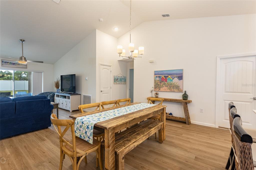 A dining area with a wooden table and bench sits in an open-concept living space — 43 FREELAND, PALM COAST, FL