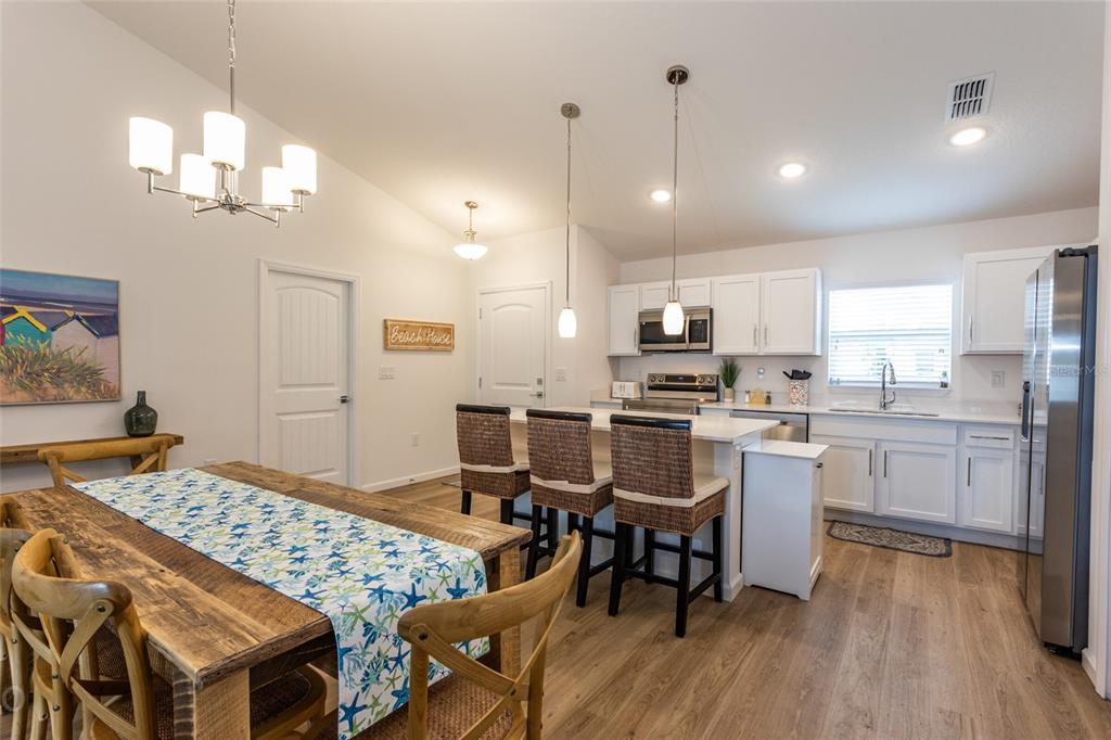 A kitchen and dining area with white cabinets, a central island, and wood-look flooring — 43 FREELAND, PALM COAST, FL