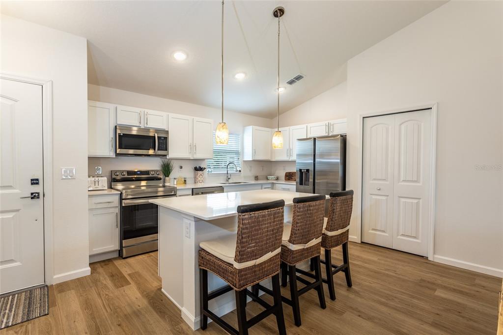 A modern kitchen features white cabinets, stainless steel appliances, a center island, and wood flooring — 43 FREELAND, PALM COAST, FL