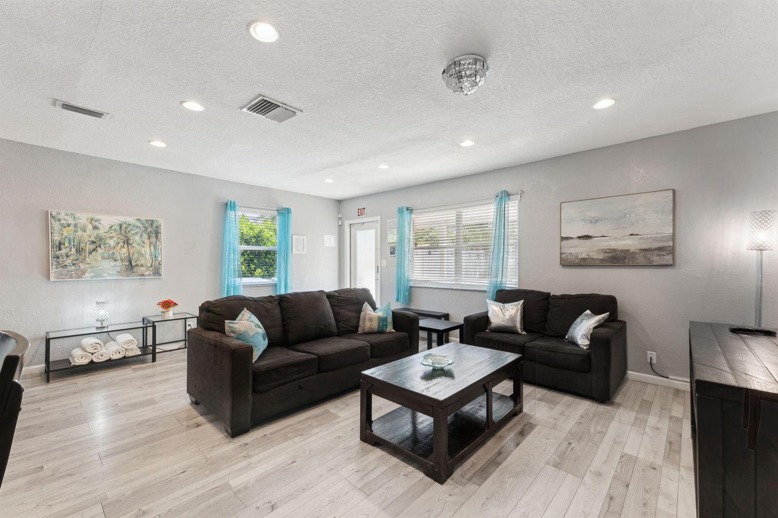 A living room features gray walls, light wood-look flooring, two dark sofas, and a coffee table — 1631 N Andrews Square, Fort Lauderdale FL 33311, FORT LAUDERDALE, FL