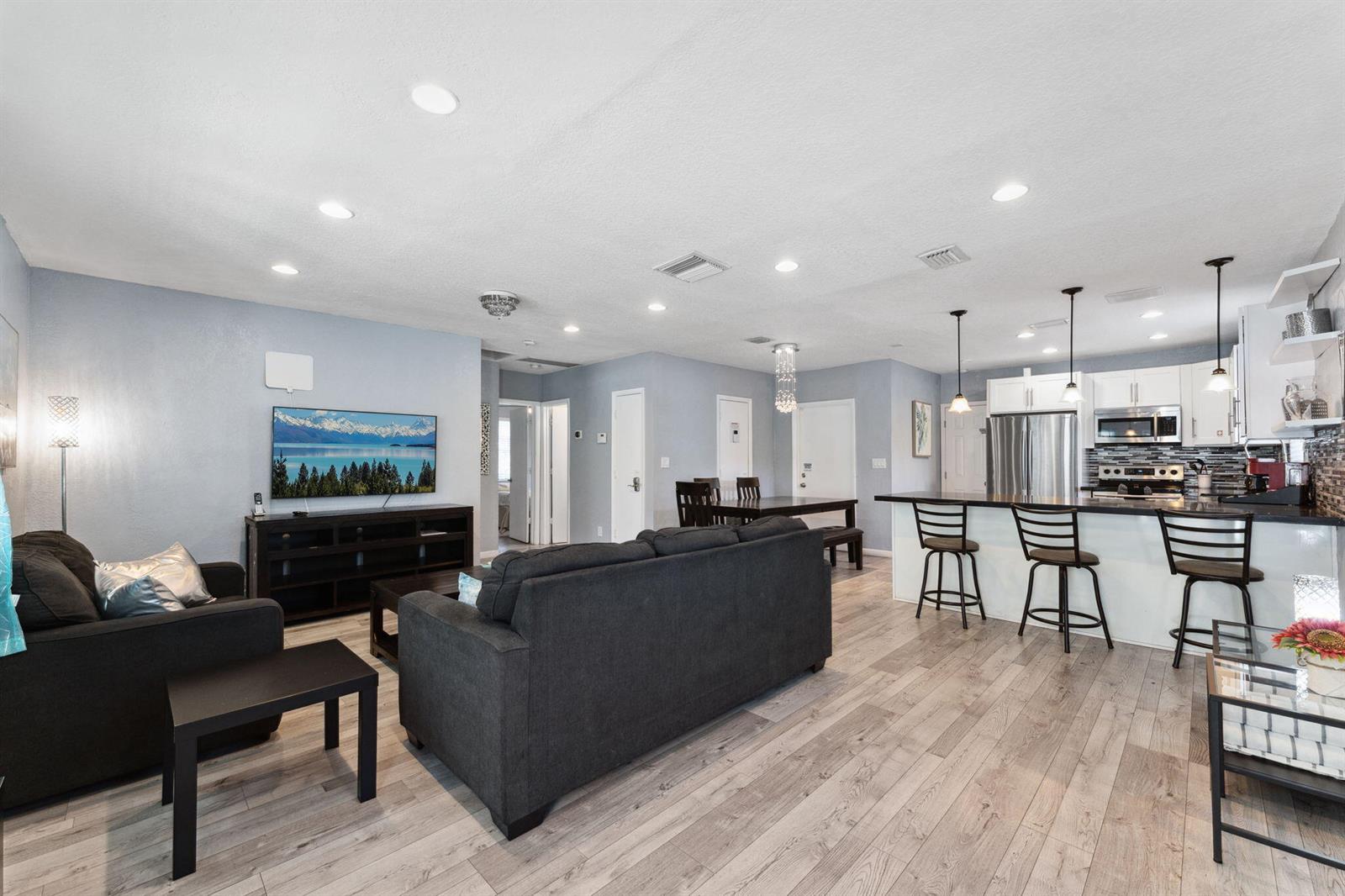A living room with gray walls and wood-look flooring opens to a kitchen with bar seating — 1631 N Andrews Square, Fort Lauderdale FL 33311, FORT LAUDERDALE, FL