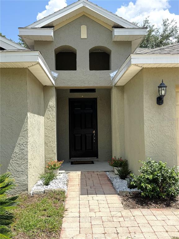 The exterior of a house features a brick walkway leading to a dark front door — 1209 BRAMLEY LANE, DELAND, FL