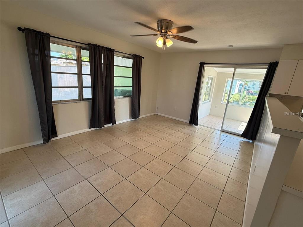 A living room features light tile flooring, a ceiling fan, and sliding glass patio doors — 22180 MIDWAY BOULEVARD, PORT CHARLOTTE, FL