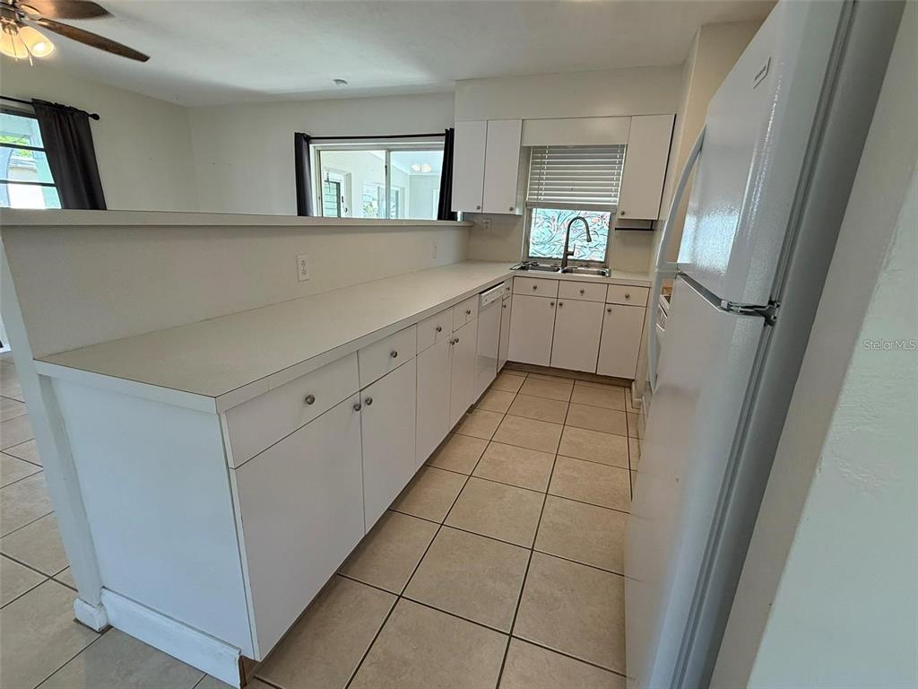 A kitchen features white cabinets, white countertops, tile flooring, and a white refrigerator — 22180 MIDWAY BOULEVARD, PORT CHARLOTTE, FL