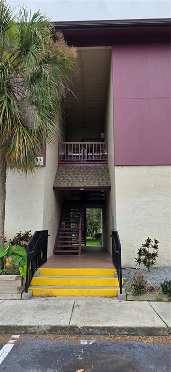 An exterior view of an apartment building entrance with yellow stairs and a wooden staircase — 3814 N LAKE DRIVE UNIT 70, TAMPA, FL