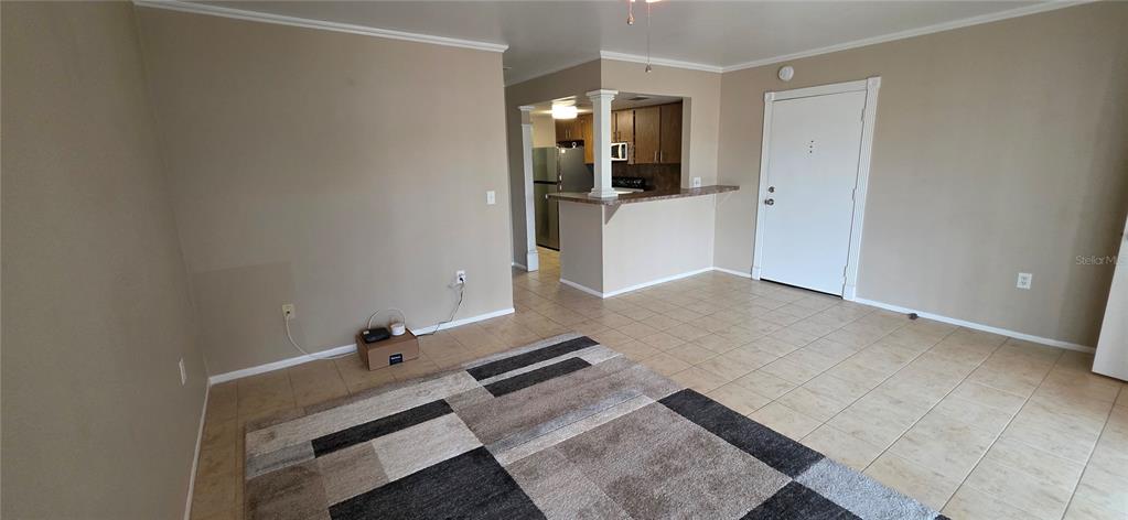 A living room with beige walls and tile flooring features a kitchen pass-through counter — 3814 N LAKE DRIVE UNIT 70, TAMPA, FL