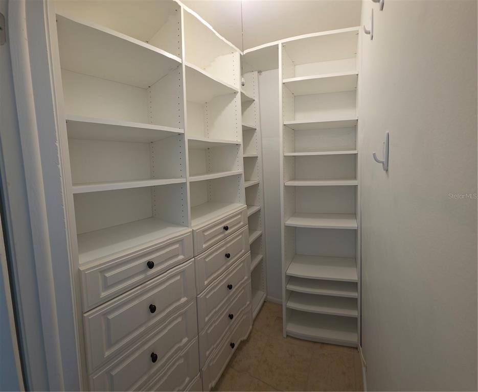 A walk-in closet features white built-in shelving, drawers, and tile flooring — 3814 N LAKE DRIVE UNIT 70, TAMPA, FL