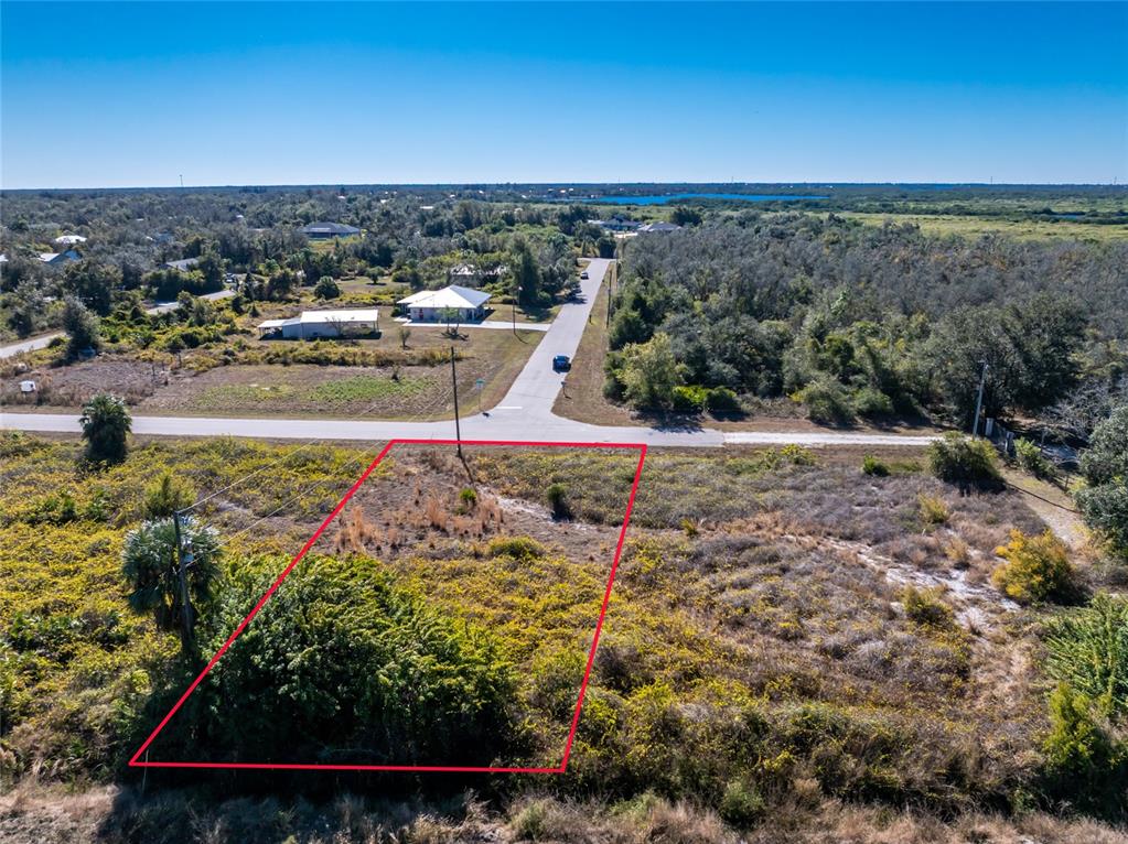 An aerial view shows a vacant, rectangular lot outlined in red next to a road — 29012 BOYCE ROAD, PUNTA GORDA, FL