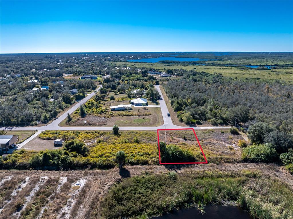 An aerial view shows a vacant, rectangular lot outlined in red near a paved road — 29012 BOYCE ROAD, PUNTA GORDA, FL