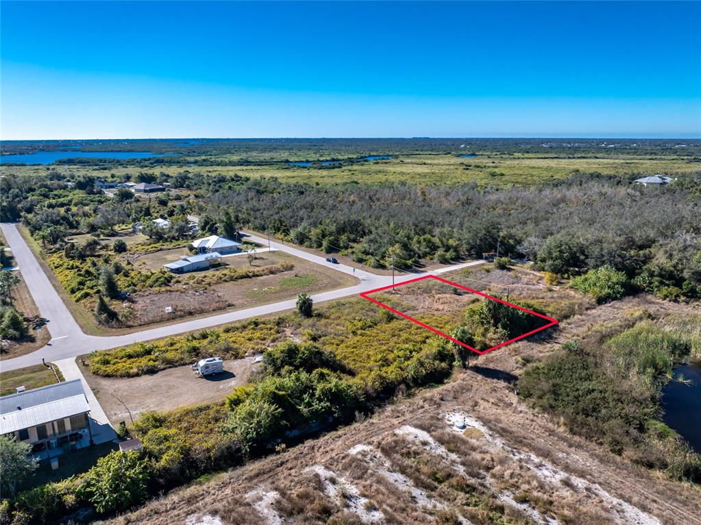 An aerial view shows a vacant, rectangular plot of land outlined in red near roads — 29012 BOYCE ROAD, PUNTA GORDA, FL