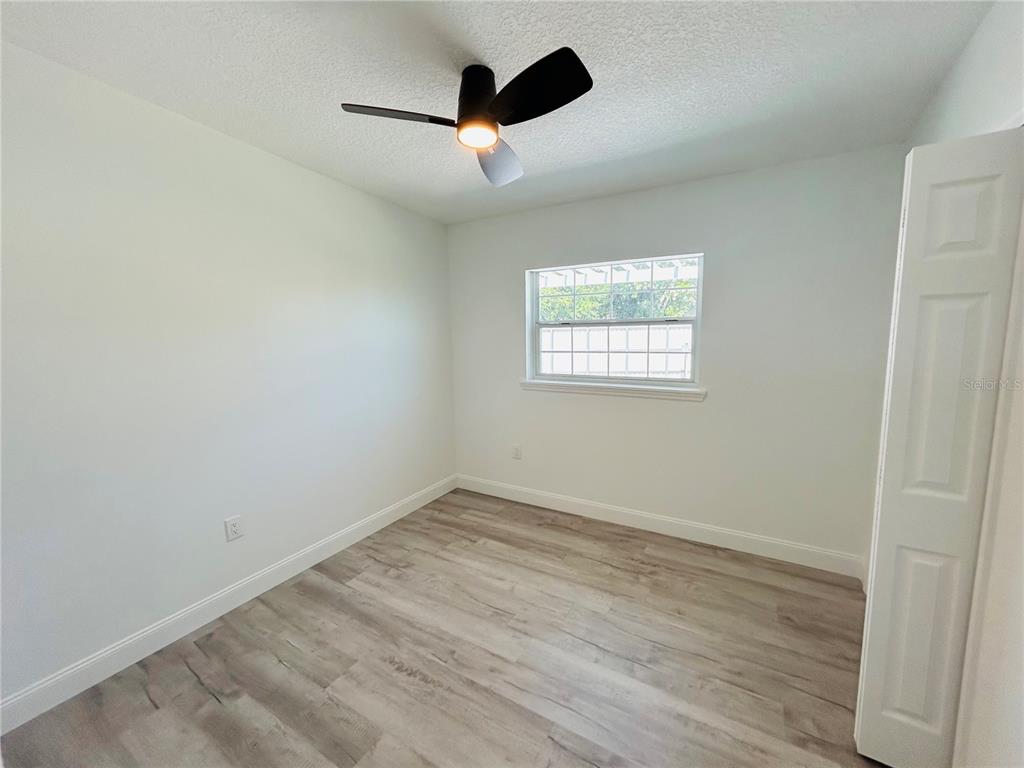 An empty bedroom features white walls, light wood-look flooring, a ceiling fan, and a window — 6603 COCOS DRIVE, ORLANDO, FL